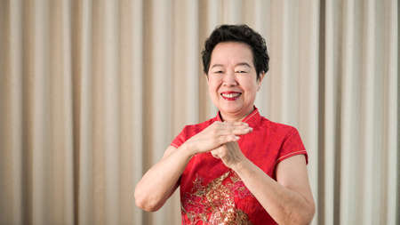 Chinese Asian senior woman in red costume New Year celebrationの写真素材
