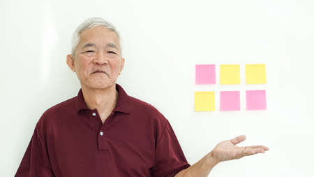 Handsome Asian senior man presenting on white copy space
