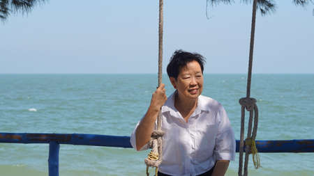 Asian senior woman alone at sea sunriseの写真素材