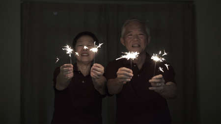 Asian senior couple playing firework, sparklers, fire cracker at night. Concept celebrating life