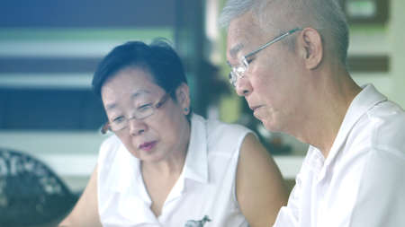 Asian senior couple reading books and magazines together in small library. Learning and study conceptの写真素材
