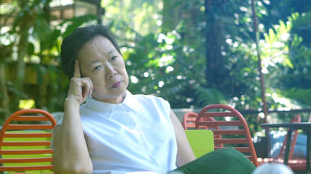 Asian senior woman thinking and stress with nature backgroundの写真素材