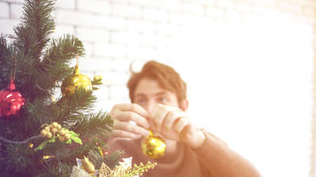 Caucasian man excited decorating Christmas tree waiting to surprise familyの写真素材