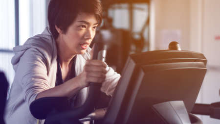 Mirror reflect Asian woman exercise gym bicycle concentration