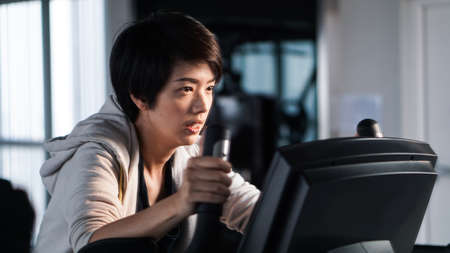 Mirror reflect Asian woman exercise gym bicycle concentrationの写真素材