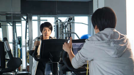 Mirror reflect Asian woman exercise gym bicycle concentrationの写真素材