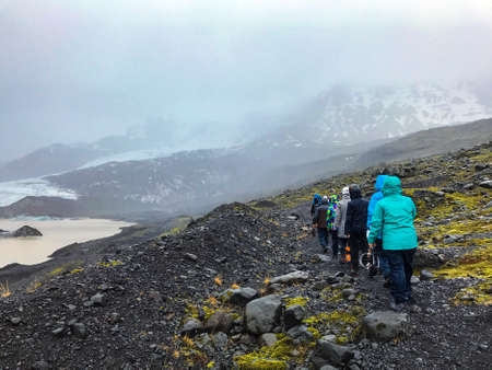 Bad weather glacier hiking in Iceland volcanic black stone landscape with ice and snow