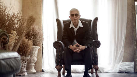 Senior Asian mafia man handsome and suit sitting in rich expensive houseの写真素材