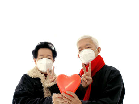 Asian Chinese elder senior couple wear mask protect coronavirus give love and encourage victory gestureの写真素材