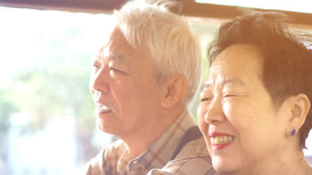 Asian elder couple have fun on public transportation morning sun light togetherの写真素材