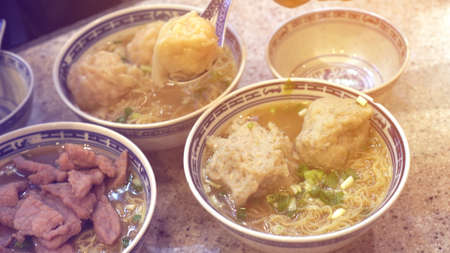 Eating Hong Kong Cantonese wonton beef and meat ball hot soup noodle
