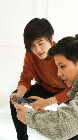 Southeast Asian friends playing smart phone togetehr in winter cloth