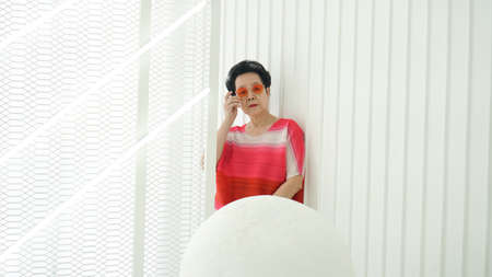 Asian female senior model red tone dress and sunglasses on white space backgroundの写真素材