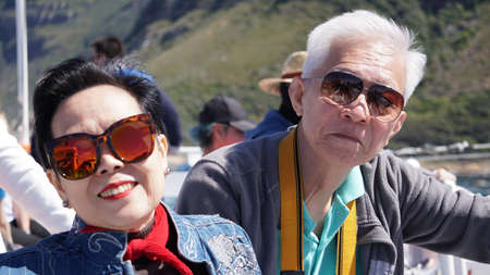 Asian senior elderly couple on tourist ferry boat False bay to seals island trip attracion Fun wildlife watching aticity in South Africa tripの写真素材