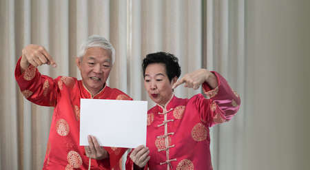 Senior elder couple in Chinese new year costume hold sign for copy space promotionの写真素材