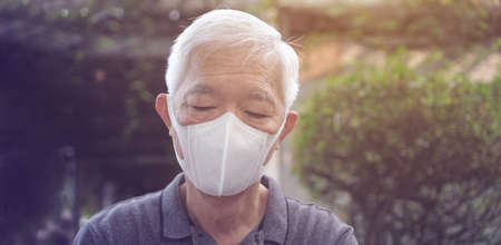 Asian senior elderly wearing mask thinking worry and stress with pandemic never ending boredの写真素材