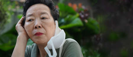 Asian senior elderly wearing mask thinking worry and stress with pandemic never ending bored