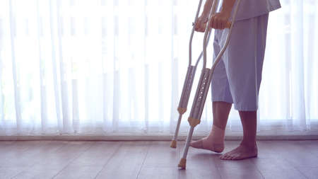 Man injured from accident using cruthes walking on wood hospital floor copy spaceの写真素材