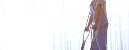 Man injured from accident using cruthes walking on wood hospital floor copy spaceの写真素材