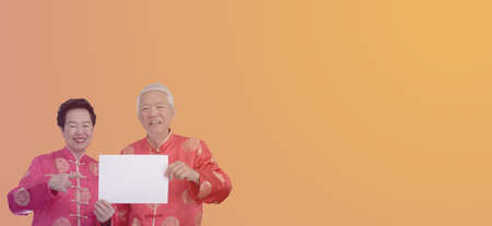 Asian senior couple Chinese new year costume holding blank sign for advertising textの写真素材