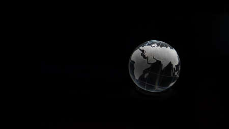 Glass crystal globe ball shine in dark background with black copy space internation global concept artの写真素材