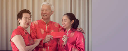 Asian family gathering Chinese New Year celebration in red traditional costume greeting red envelopの写真素材