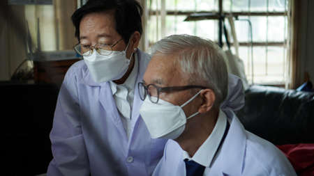 Two Asian senior doctor health care technician looking at patient information and discussing computer screenの写真素材