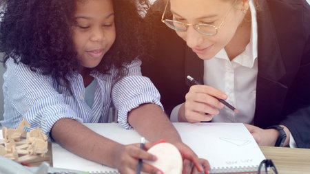 Creative class in diversity school Caucasian teacher with African kid having fun learning critical thinking global citizen education conceptualの写真素材