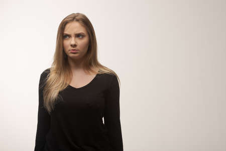 Portrait of angry and sad young woman isolated in studio white backgroundの写真素材