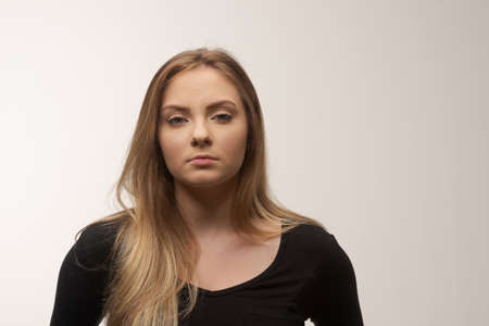 Portrait of angry and sad young woman isolated in studio white backgroundの写真素材