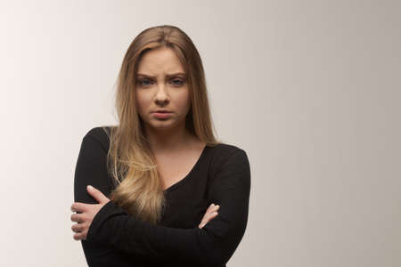 Portrait of angry and sad young woman isolated in studio white backgroundの写真素材