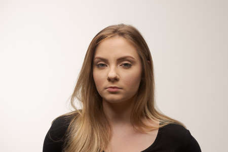 Portrait of angry and sad young woman isolated in studio white backgroundの写真素材