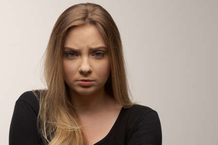 Portrait of angry and sad young woman isolated in studio white backgroundの写真素材