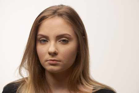 Portrait of angry and sad young woman isolated in studio white backgroundの写真素材