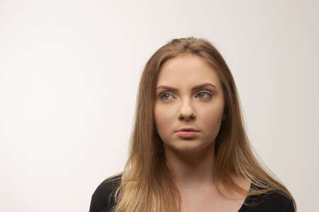Portrait of angry and sad young woman isolated in studio white backgroundの写真素材