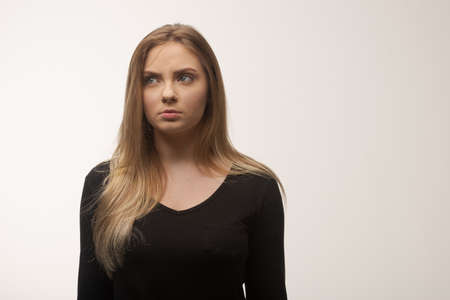 Portrait of angry and sad young woman isolated in studio white backgroundの写真素材