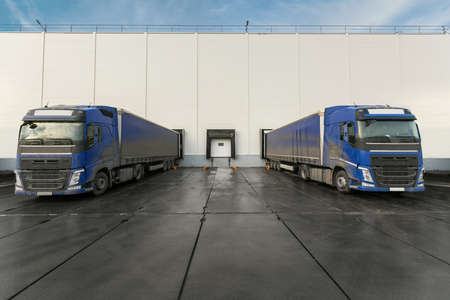 white truck with a white trailer at unloading at the warehouse.Warehouse complex with an asphalt pad and truck with blue skyの写真素材