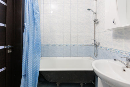 modern bathroom with white tiles, blue shower curtain and classic bathtubの写真素材