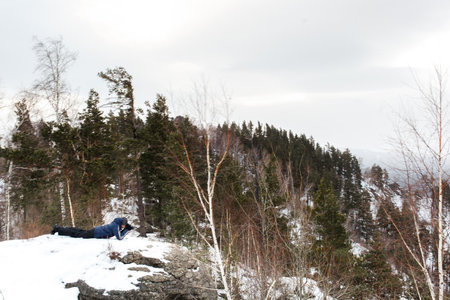 Man lying on a rock in the winter forest. View from above.
