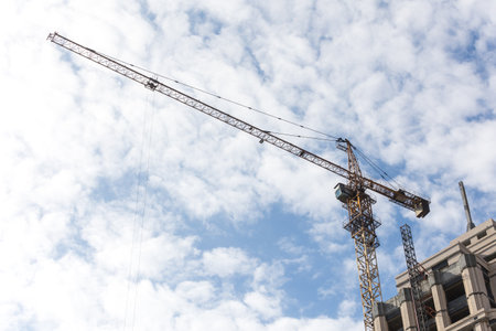 Construction site with cranes and building under construction against blue sky.の写真素材