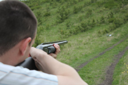 Man aiming a gun at the hill. Focus on the gun.の写真素材