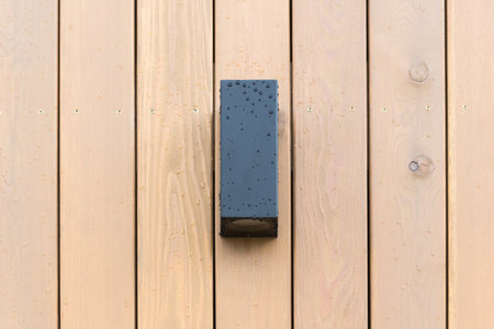 black front lamp on the wooden facade of a house with rain or dew drops