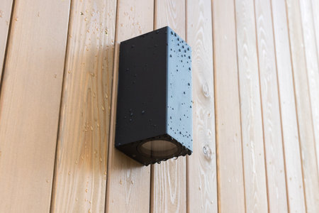 black front lamp on the wooden facade of a house with rain or dew dropsの写真素材