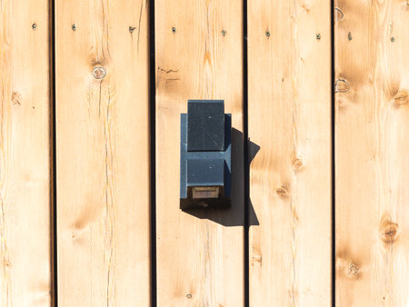 black front lamp on the wooden facade of the house on a sunny day