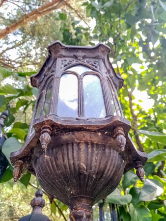 Old broken vintage street lamp stands on a green wood backgroundの写真素材
