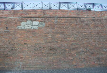 Brick wall overgrown with grass and moss. Pledged window with red brick.の写真素材