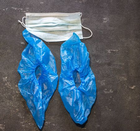 Medical mask and shoe covers on a black background. Virus and Flu Controlの写真素材