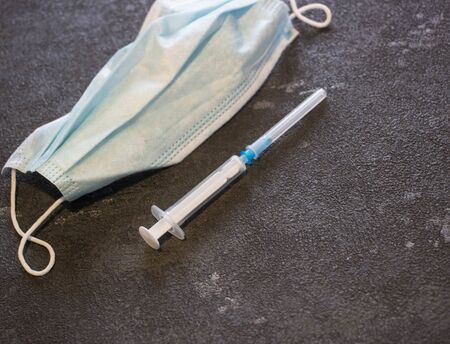 Medical mask and syringe on a black background. Coronavirus and flu remedy.の写真素材