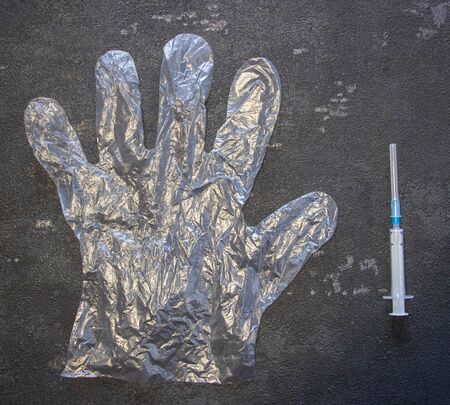 Transparent gloves and a medical syringe on a black background. Coronavirus and flu remedy.の写真素材