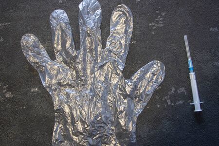 Transparent gloves and a medical syringe on a black background. Coronavirus and flu remedy.の写真素材